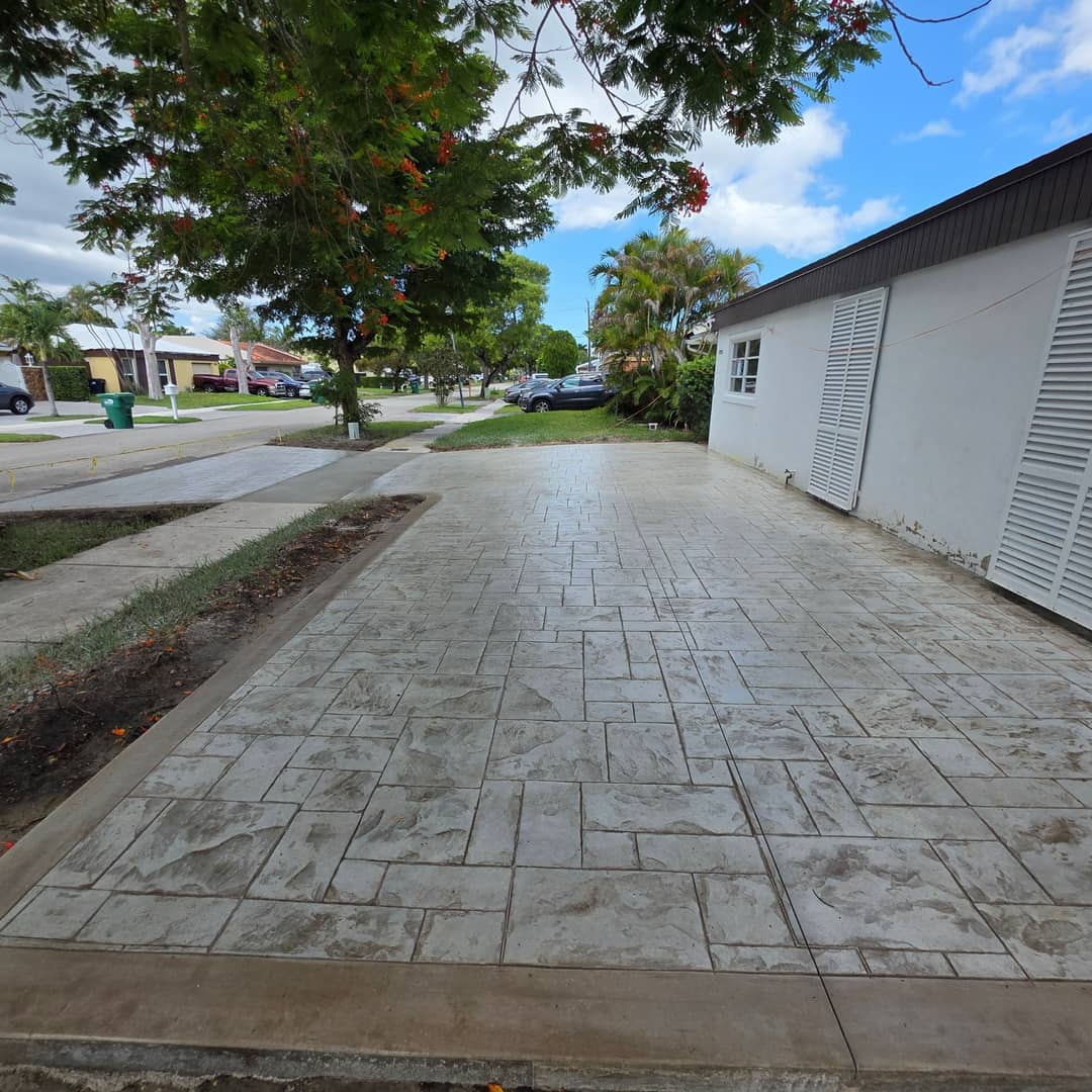 Amplia entrada de concreto con juntas de césped frente a una casa de dos plantas en el sur de la Florida